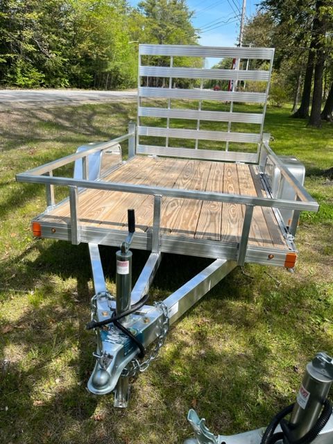 A trailer is sitting on top of a lush green field.
