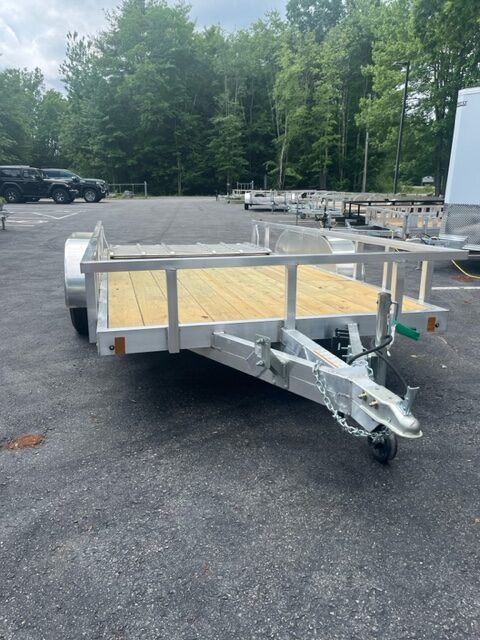 A trailer with a wooden deck is parked in a parking lot.