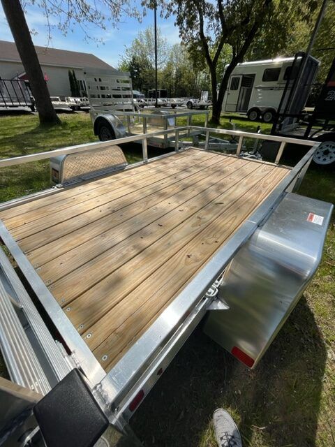 A trailer with a wooden deck is parked in the grass.