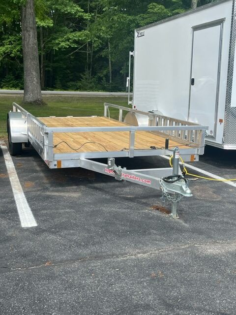 A trailer is parked in a parking lot next to a white trailer.