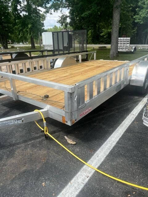 A trailer with a wooden deck is parked in a parking lot