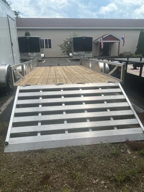 A trailer with a ramp attached to it is parked in front of a building