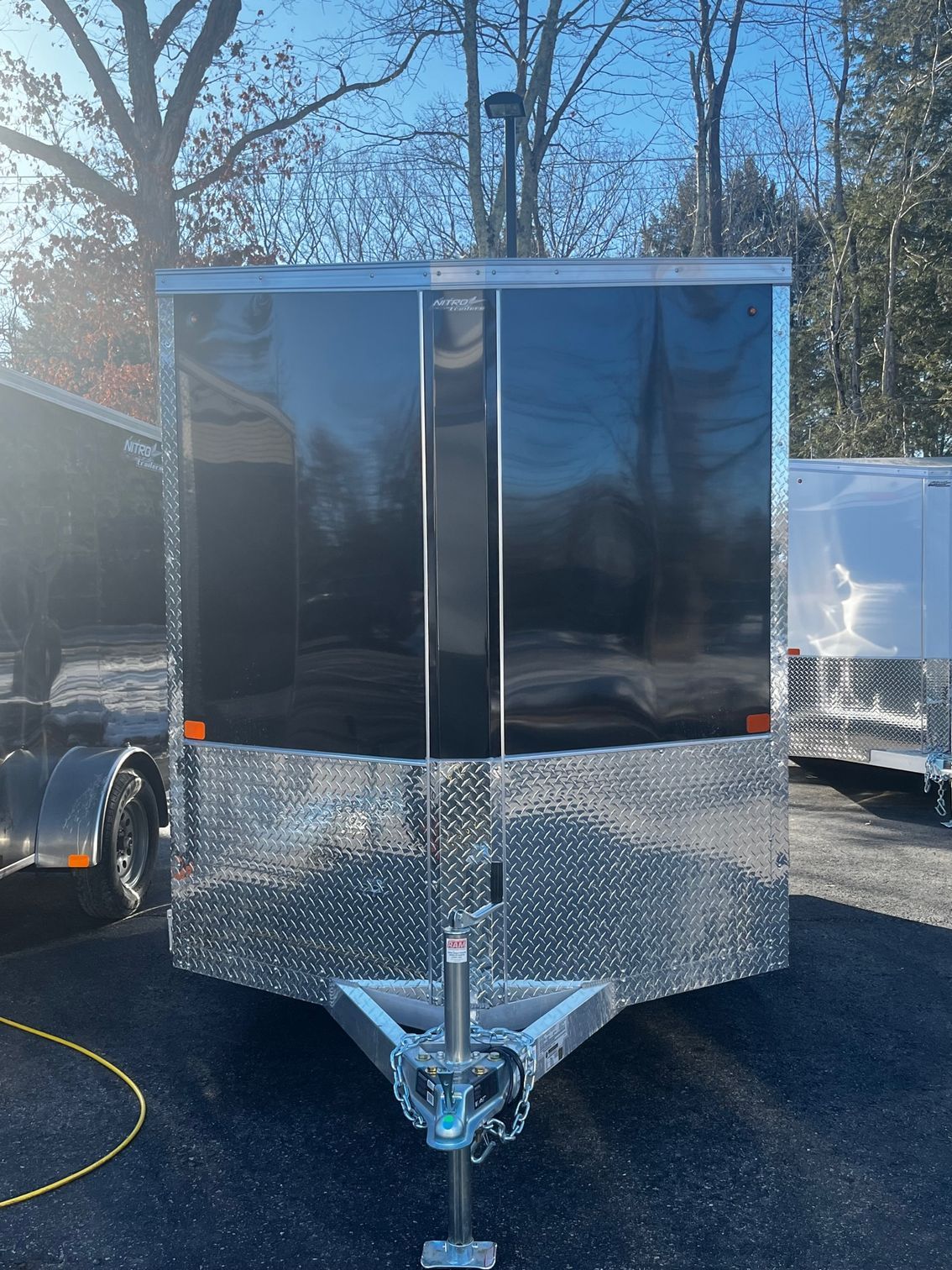 A black and silver trailer is parked in a parking lot.