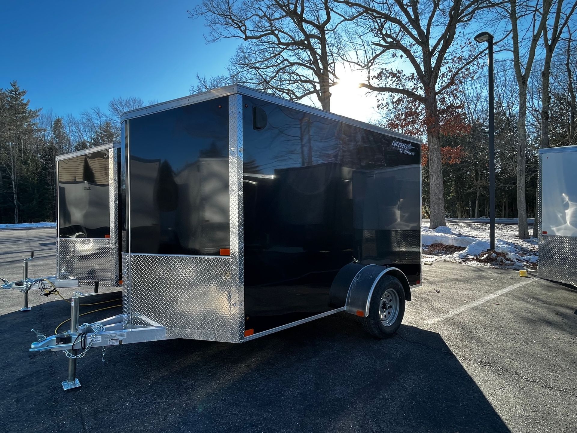 A black and silver trailer is parked in a parking lot.