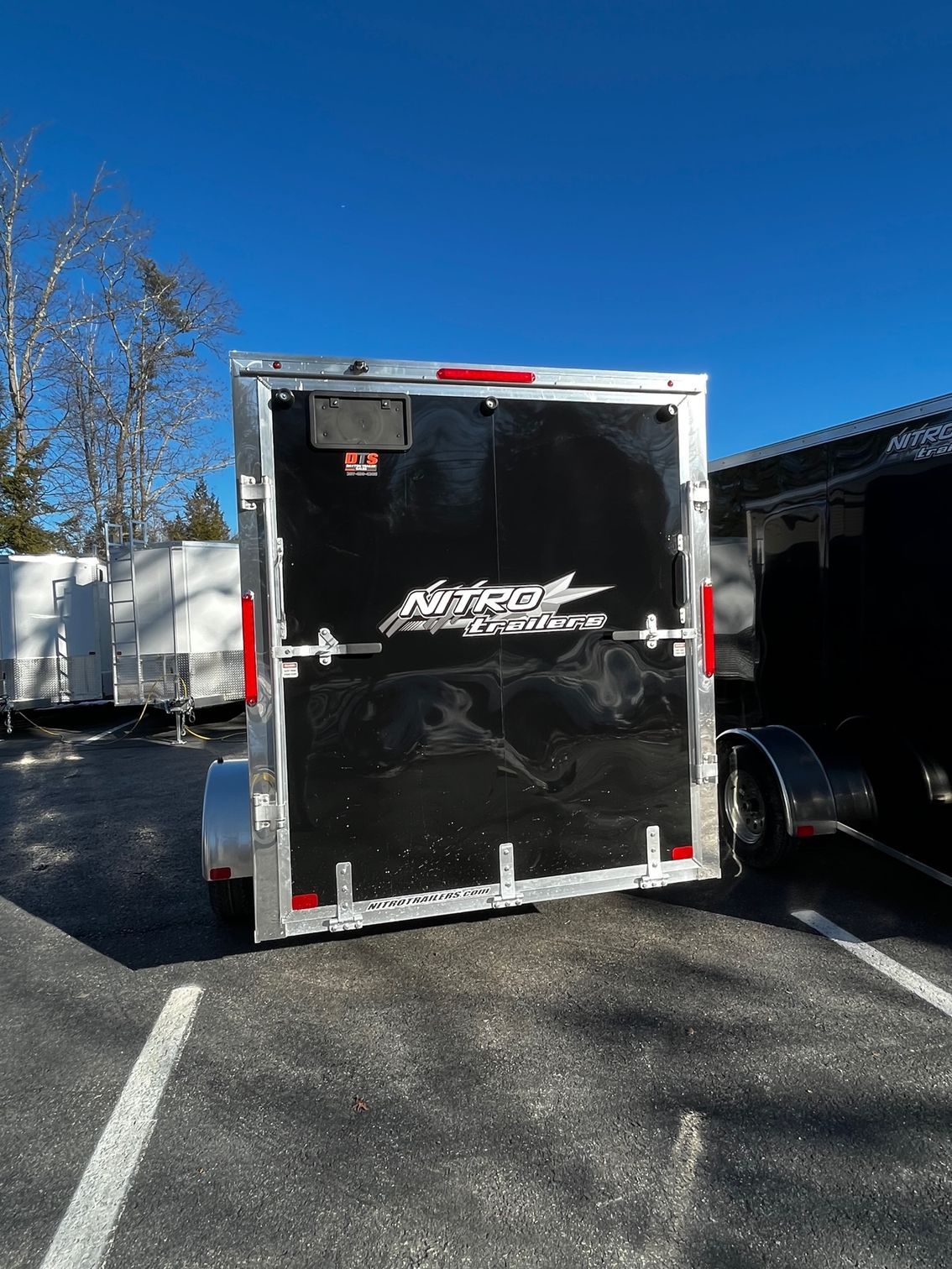 A black trailer is parked in a parking lot.