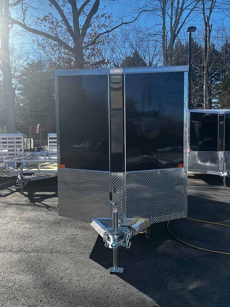 A trailer is parked in a parking lot with trees in the background.