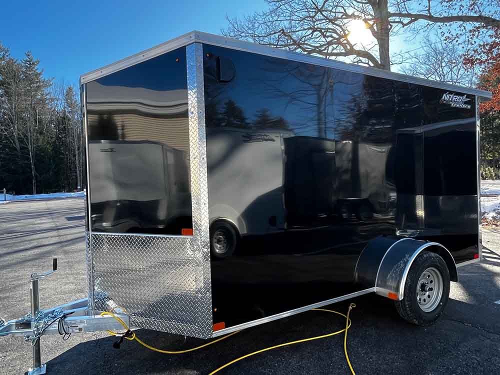 A black trailer is parked on the side of the road.