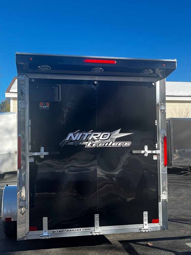 A black trailer is parked in a parking lot.