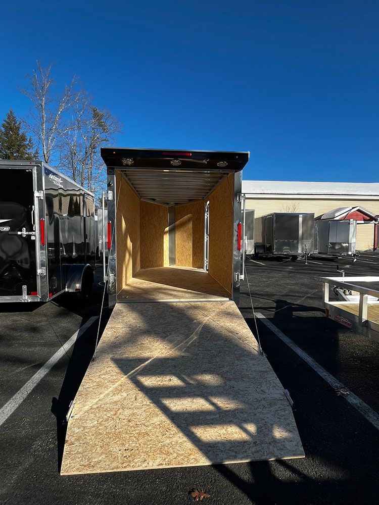 A trailer with a ramp leading to it is parked in a parking lot.