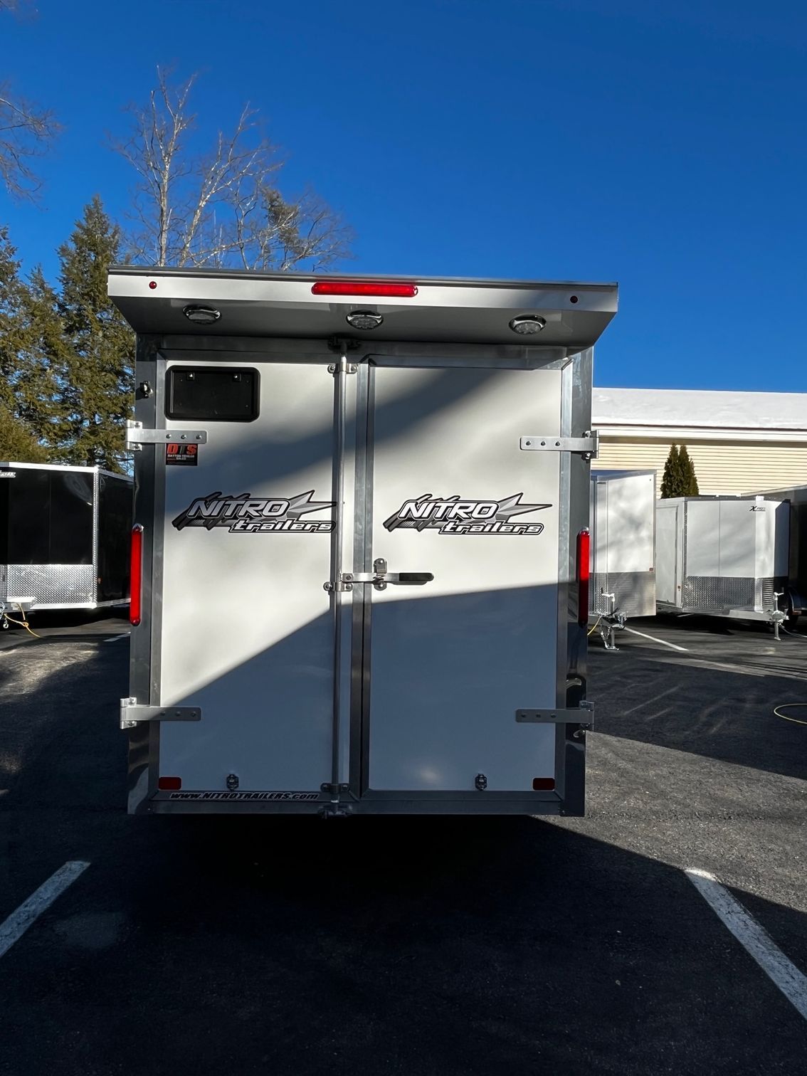 A white trailer is parked in a parking lot