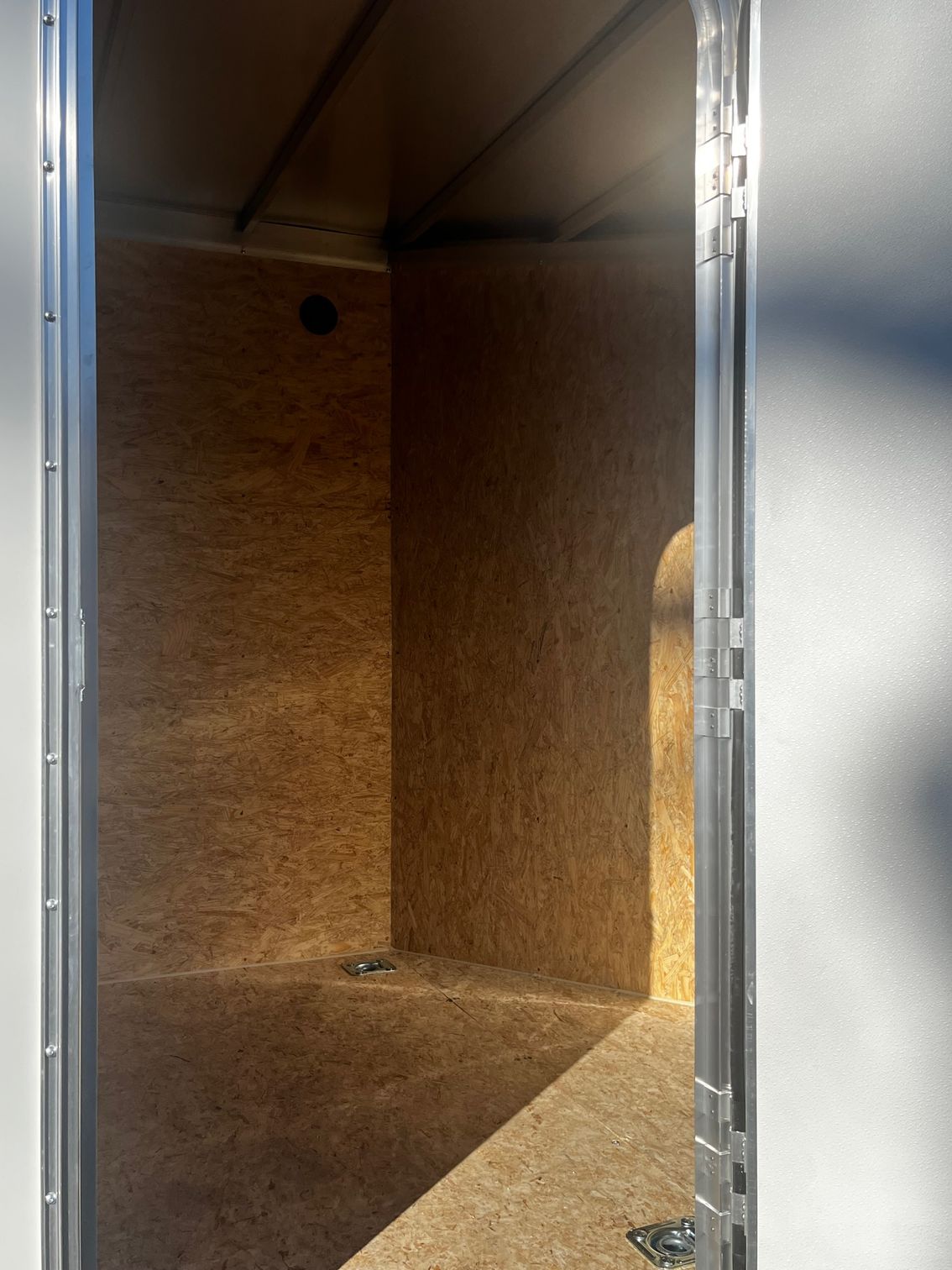 A door is open to an empty room with a wooden floor.