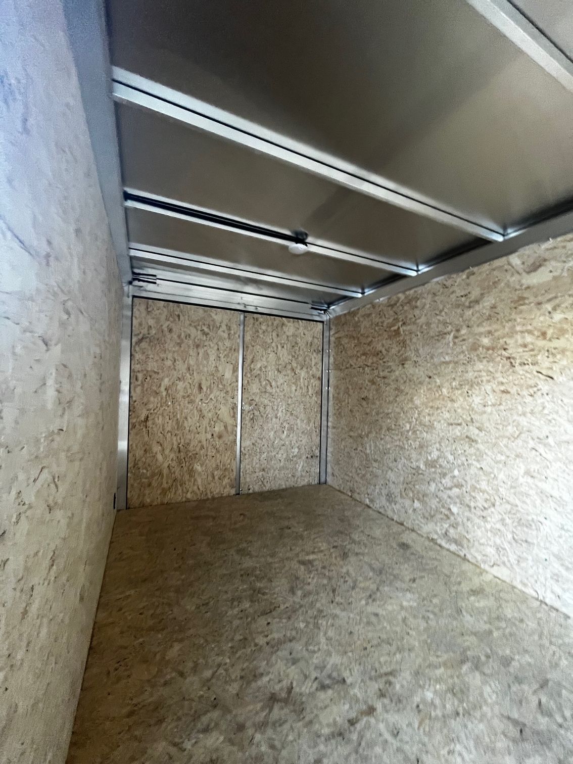 A large empty trailer with a wooden floor and a metal ceiling