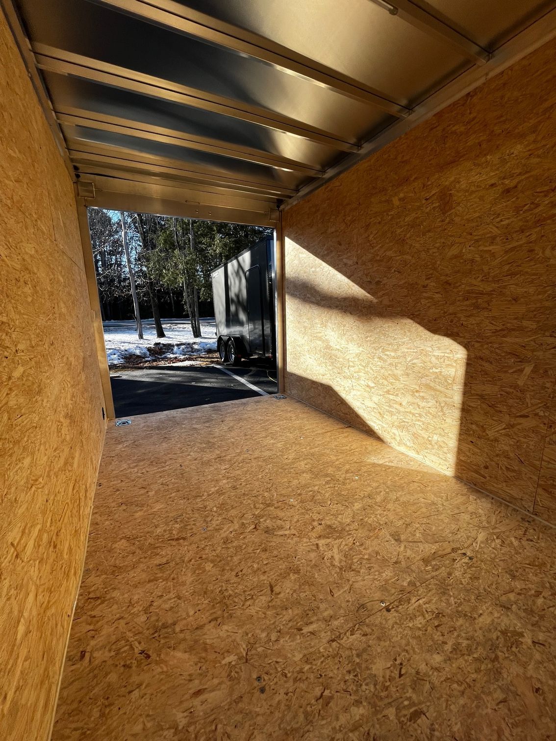 The inside of an empty trailer with a truck parked in the background.
