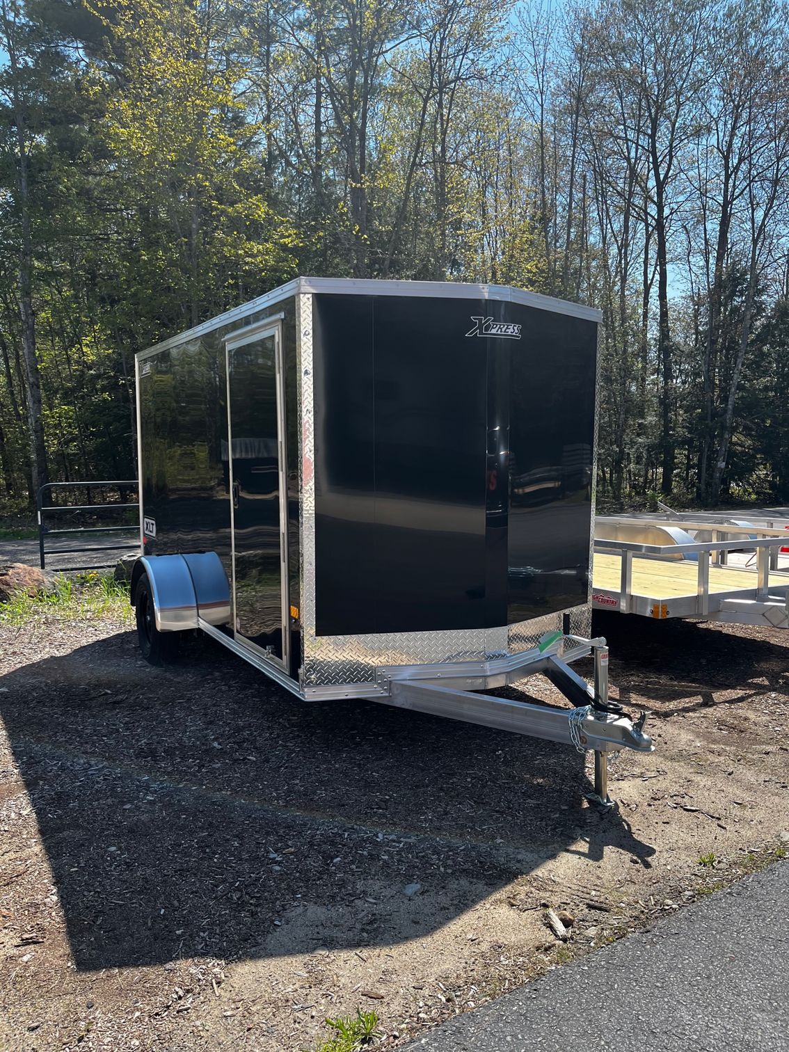 A black trailer is parked on the side of the road.
