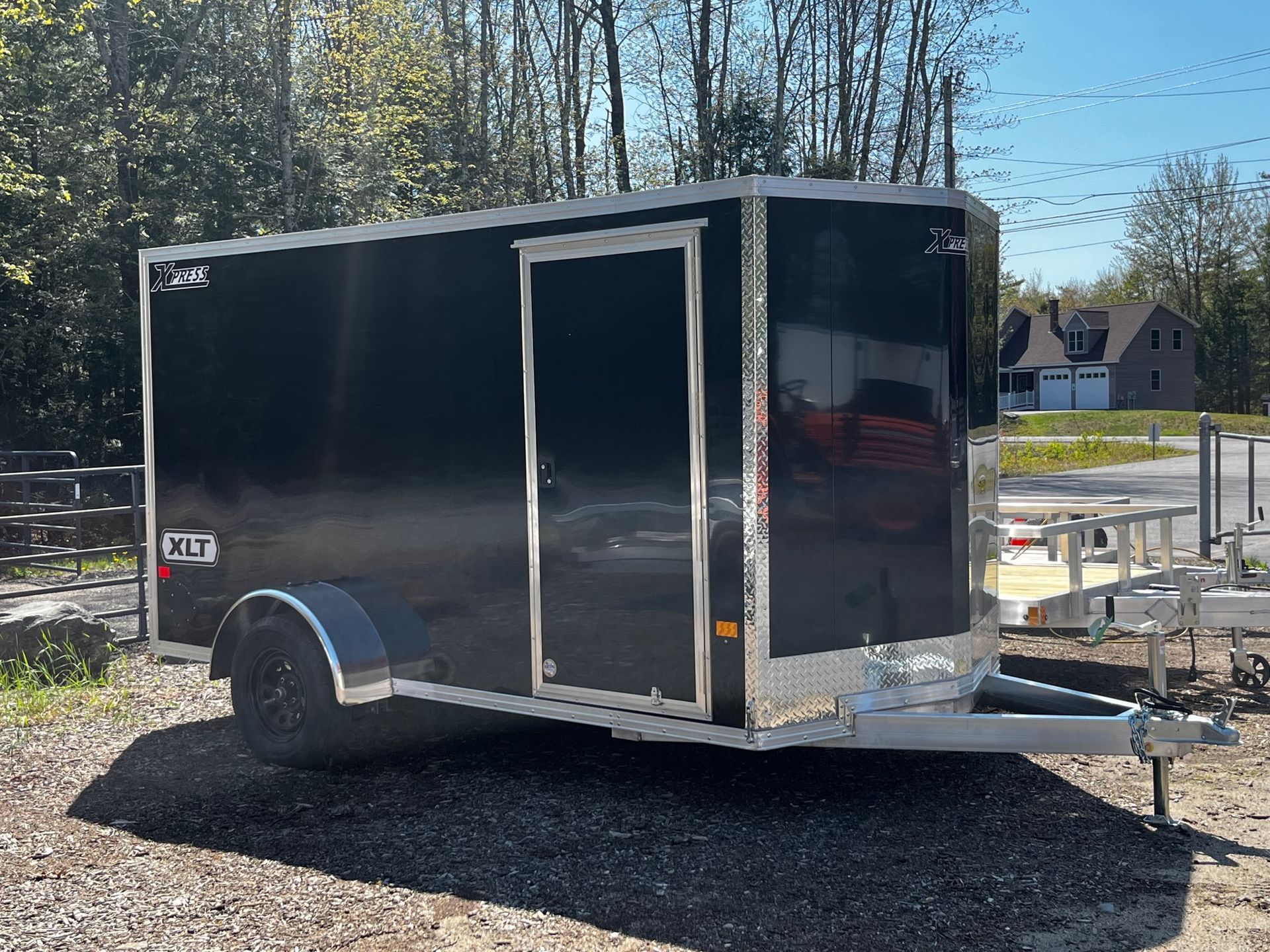 A black trailer is parked on the side of the road.
