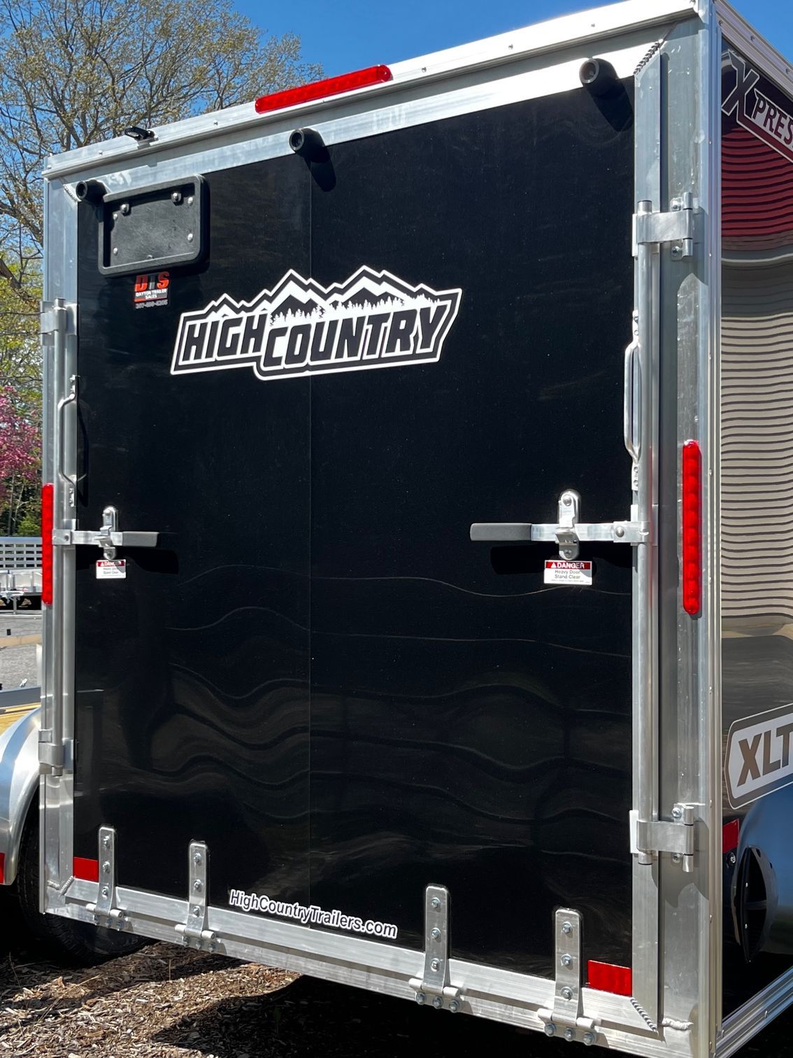 A black high country trailer is parked in a parking lot.