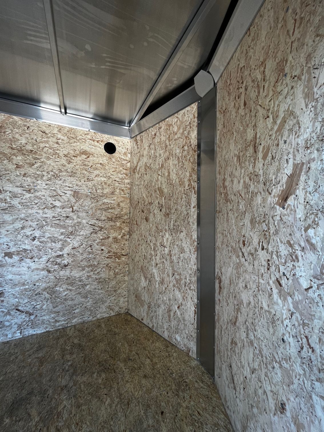 A room with a ceiling and a wall made of plywood.