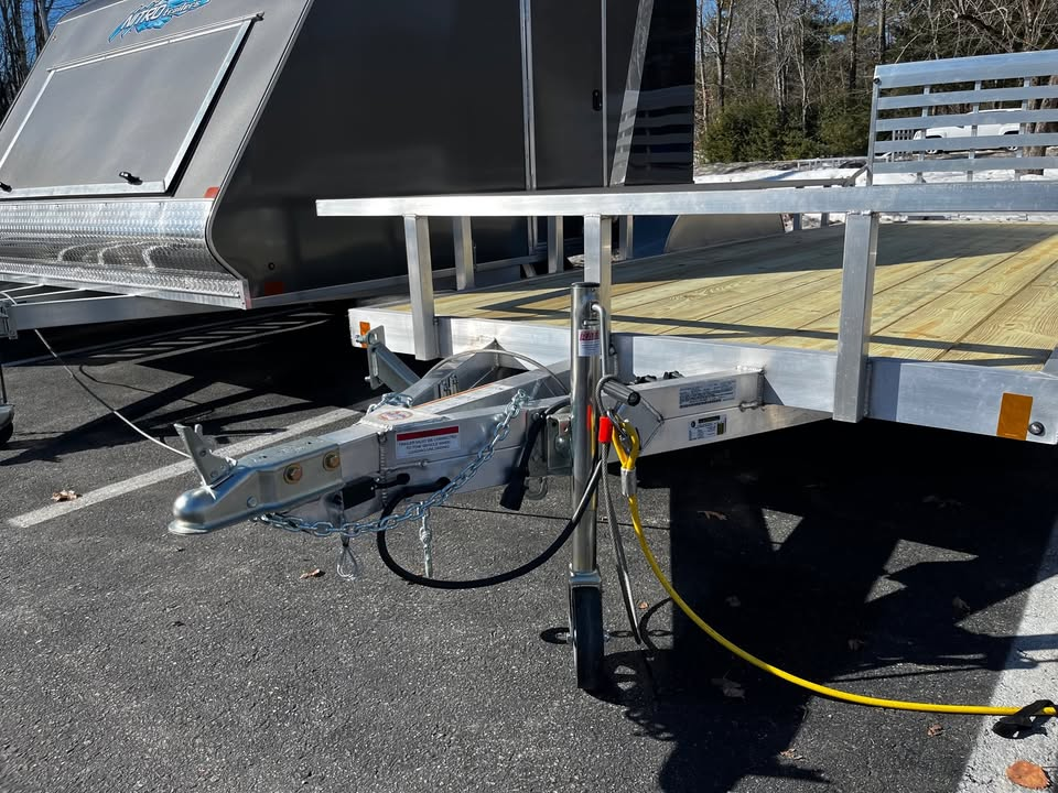 A trailer with a wooden deck attached to it is parked in a parking lot.