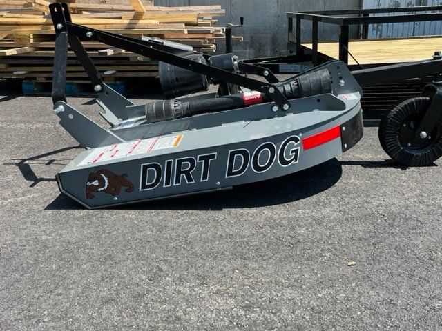 A dirt dog lawn mower is parked in a parking lot next to a trailer.