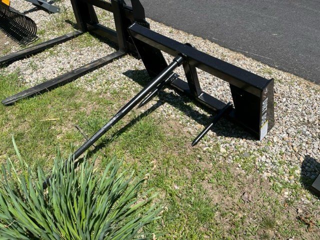 A black fork is sitting in the grass next to a plant