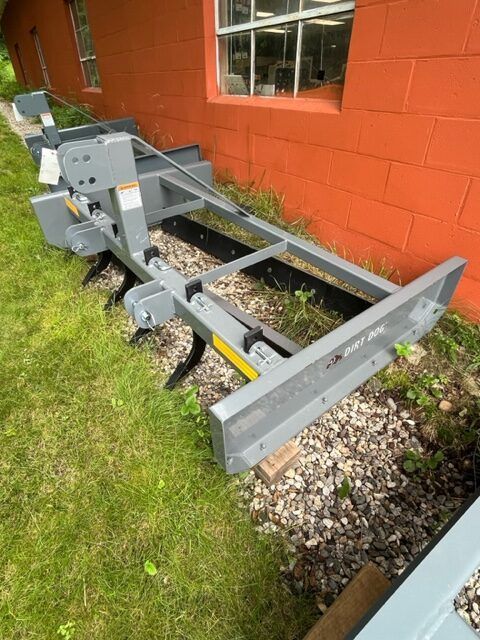 A large piece of equipment is sitting in the grass in front of a brick building