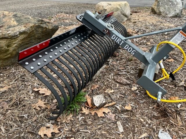 A dirt dog rake is sitting on the ground