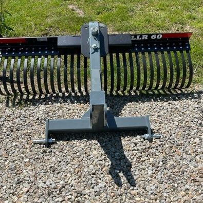 A rake is sitting on top of a gravel road.