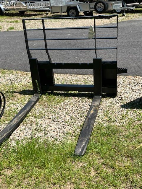 A pair of forks are sitting in the grass next to a trailer.