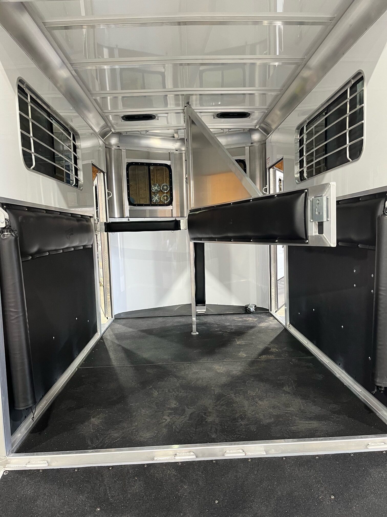 The inside of a horse trailer with a black rubber floor.