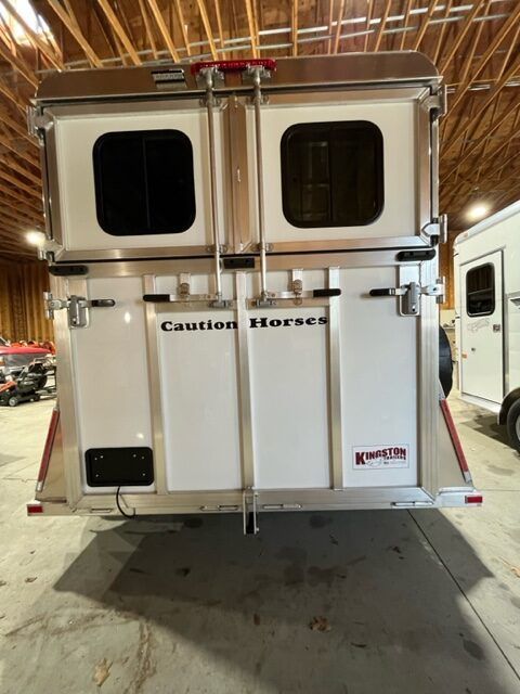 A white horse trailer is parked in a warehouse.