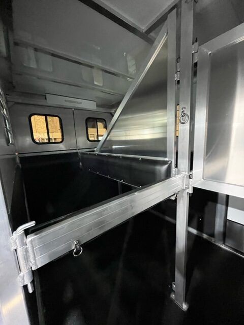 The inside of a trailer with a stainless steel shelf and a window.