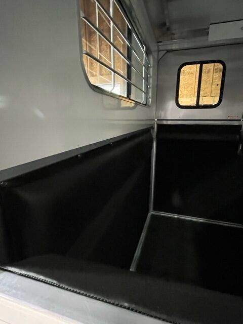 The inside of a horse trailer with a black seat and a window.