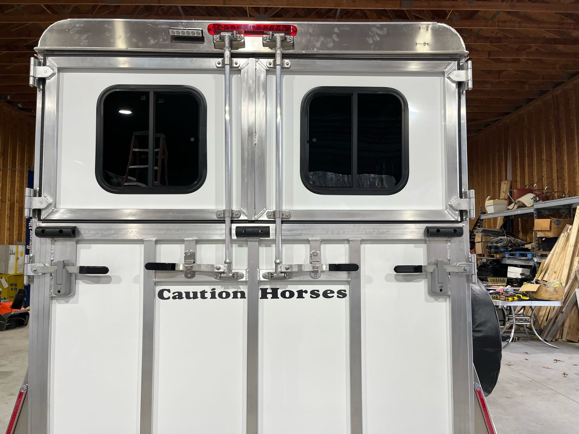 A white horse trailer is parked in a warehouse.