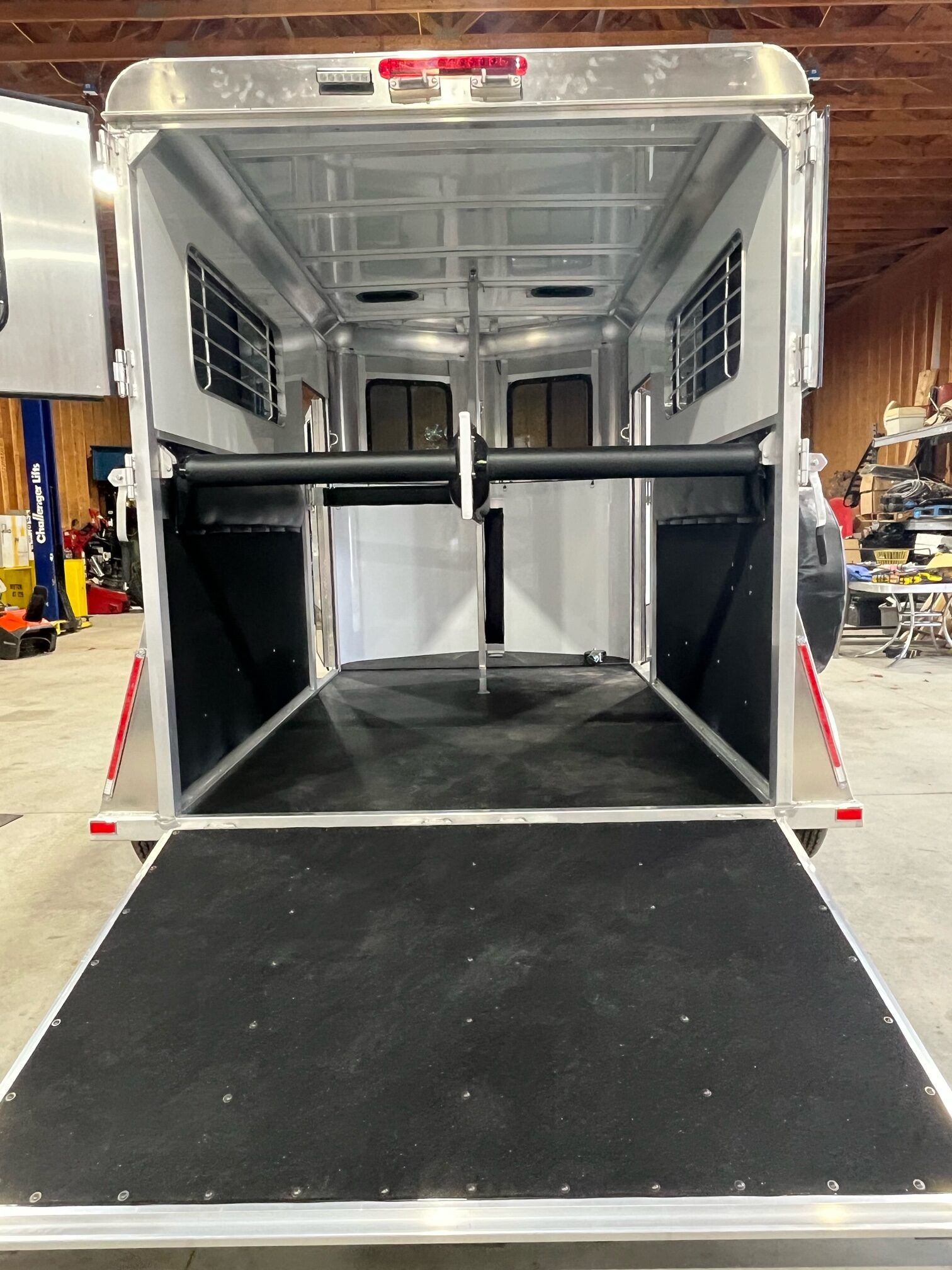The back of a horse trailer with the door open in a garage.