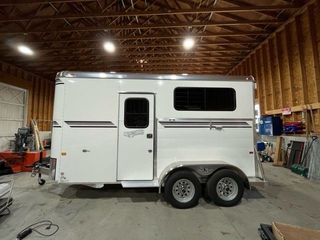 A white horse trailer is parked inside of a building