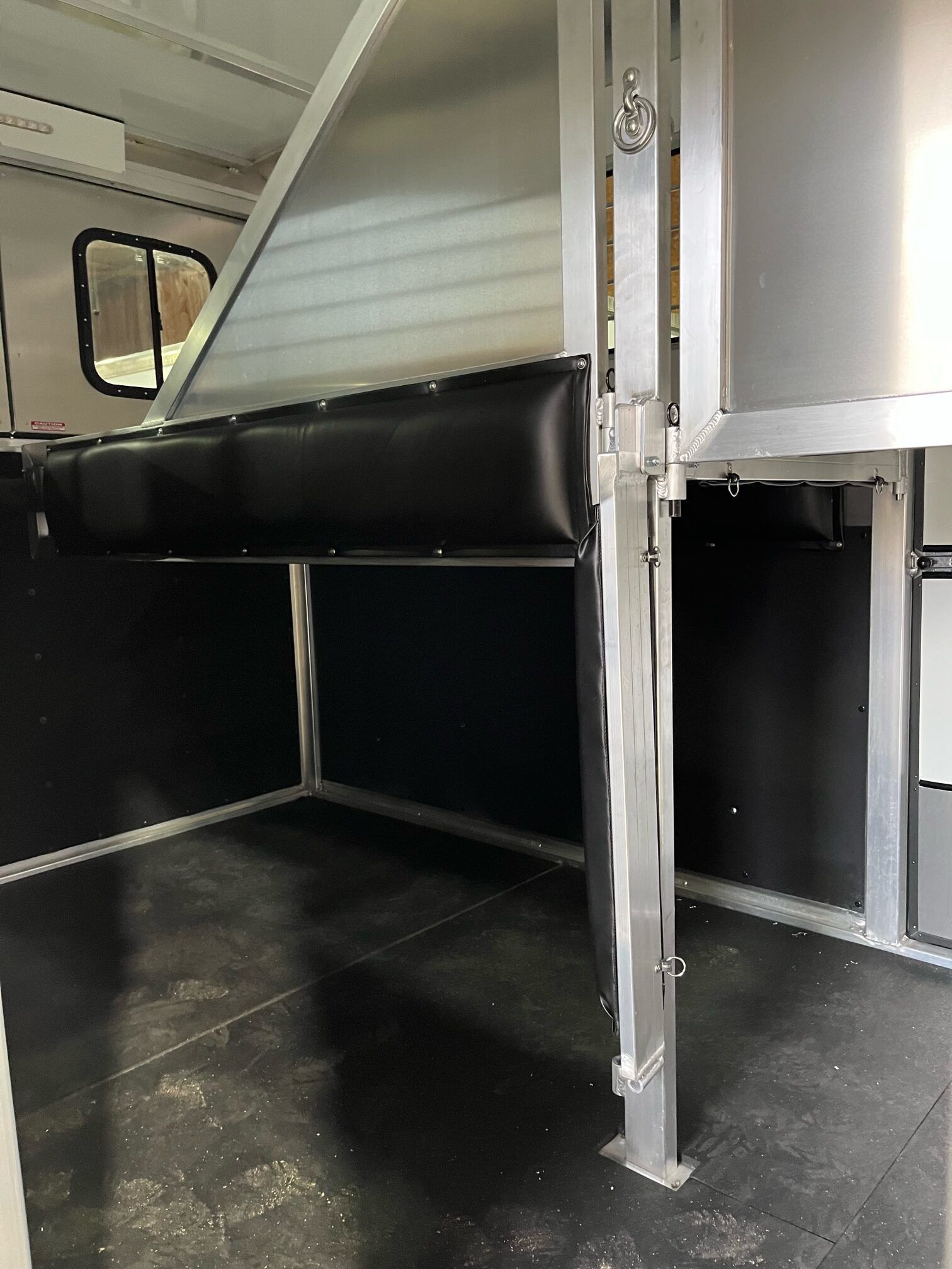 The inside of a horse trailer with a black seat and a window.