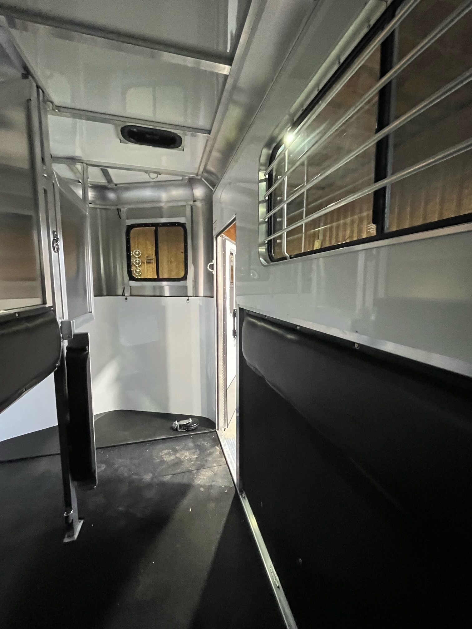 The inside of a horse trailer with a fence and windows.