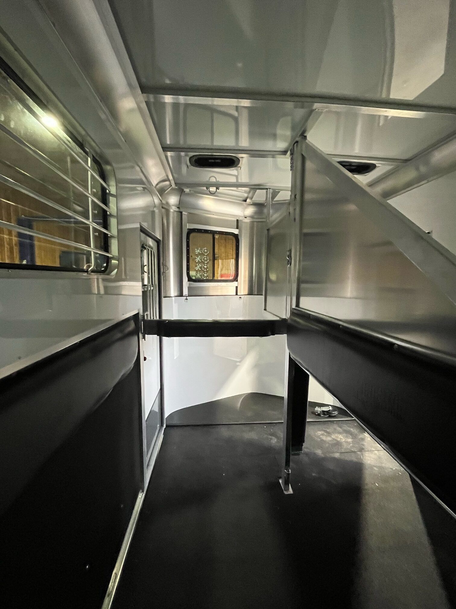 The inside of a horse trailer with a fence and a window.