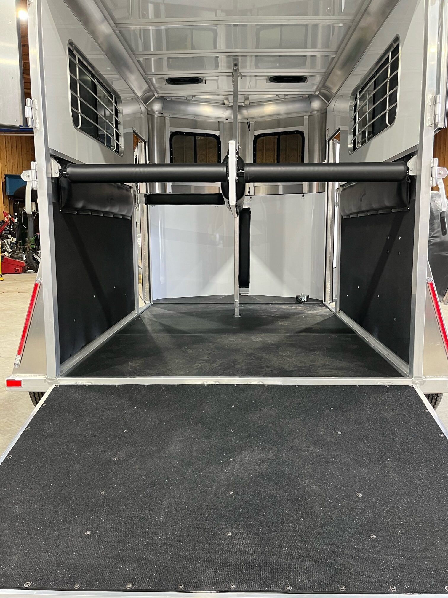 The inside of a horse trailer with a black mat on the floor.