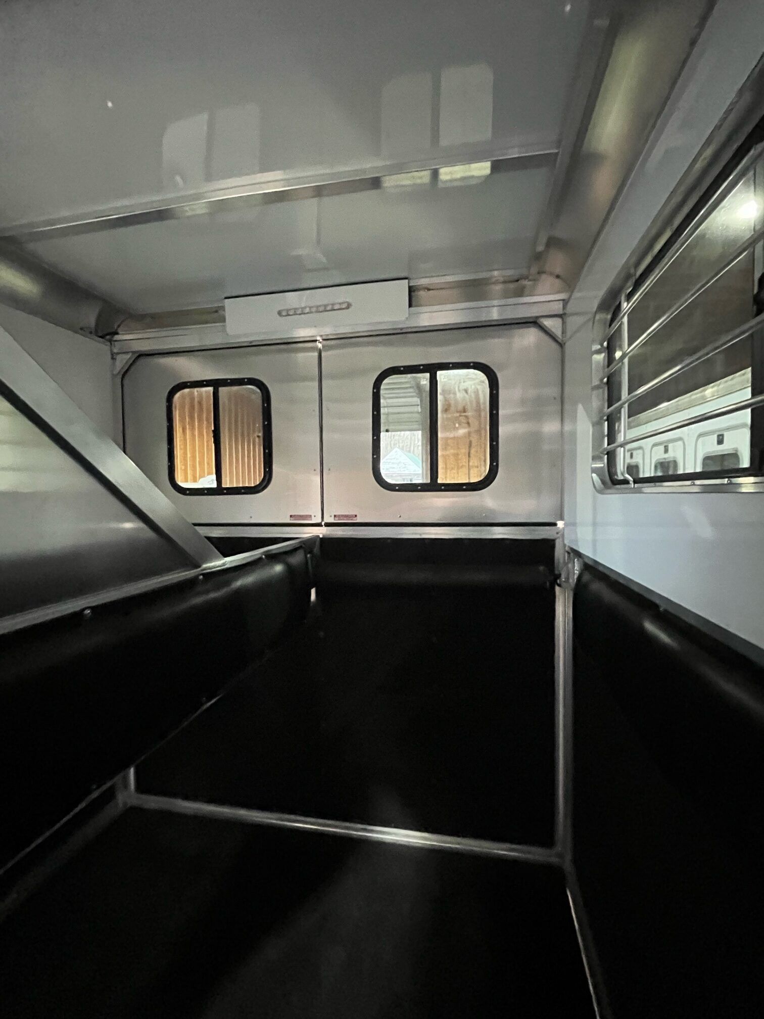 The inside of a horse trailer with two windows.