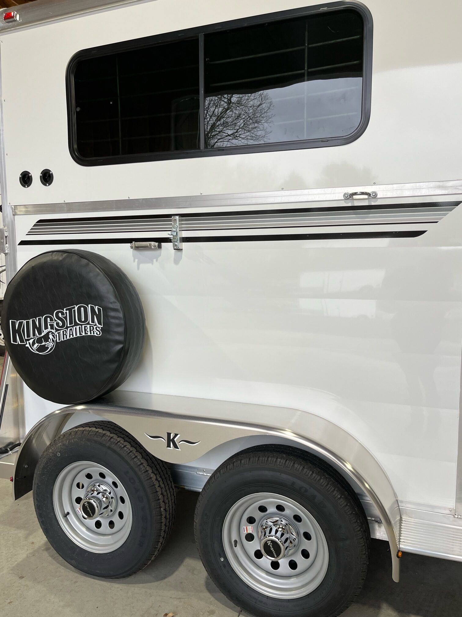 A white horse trailer with a black tire cover on the back.