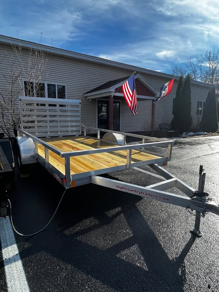 A trailer with a wooden deck is parked in front of a building.