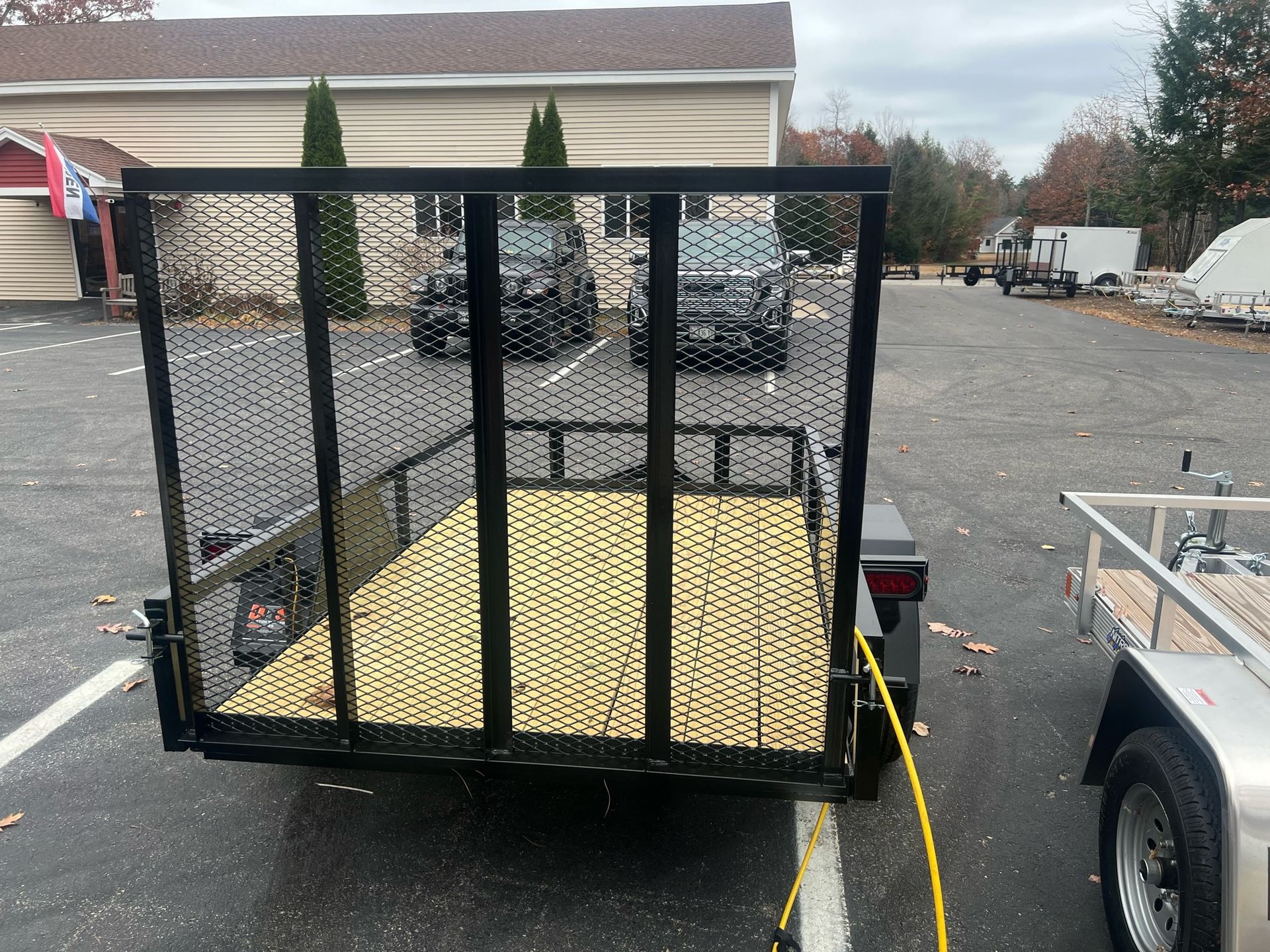 A trailer with a fence attached to it is parked in a parking lot