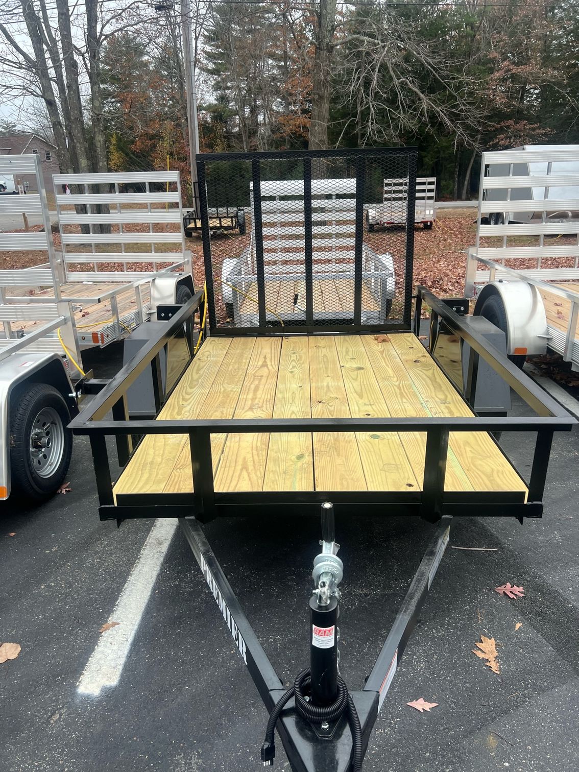 A trailer with a wooden deck is parked in a parking lot