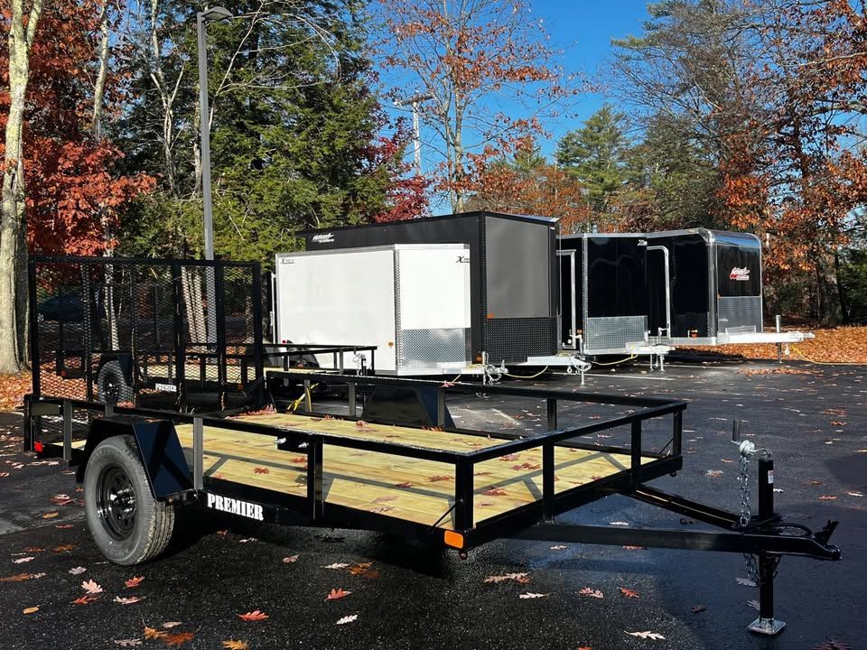 A trailer with a wooden deck is parked in a parking lot.