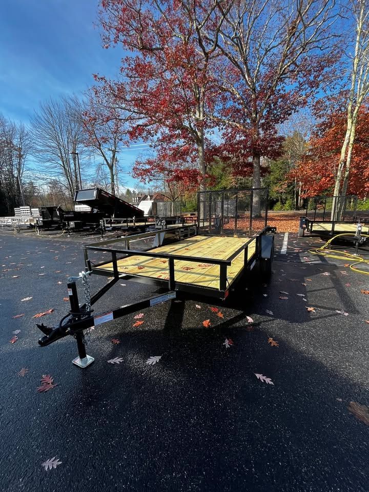 A trailer is parked in a parking lot with trees in the background.