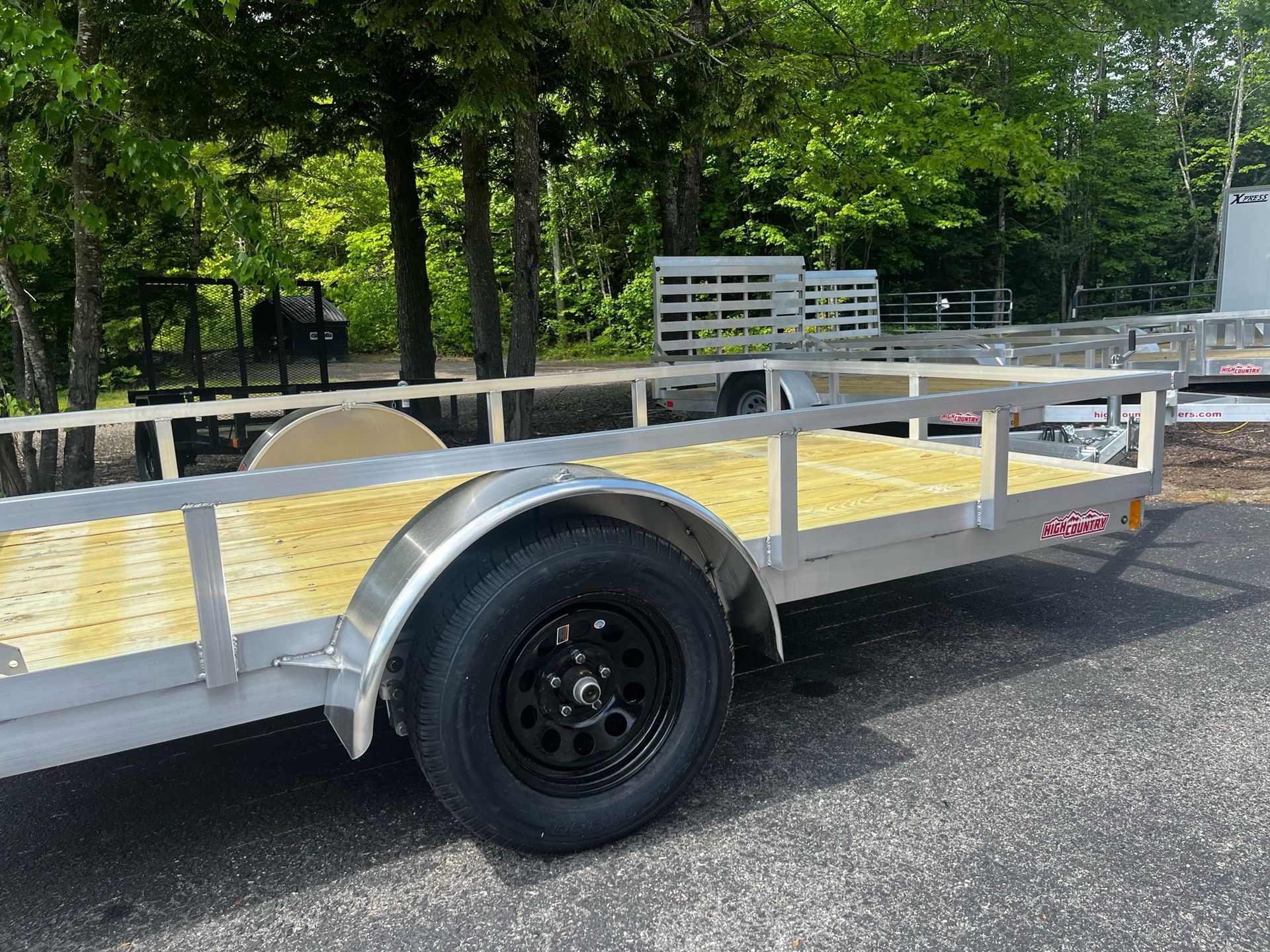 A trailer with a wooden deck is parked on the side of the road.