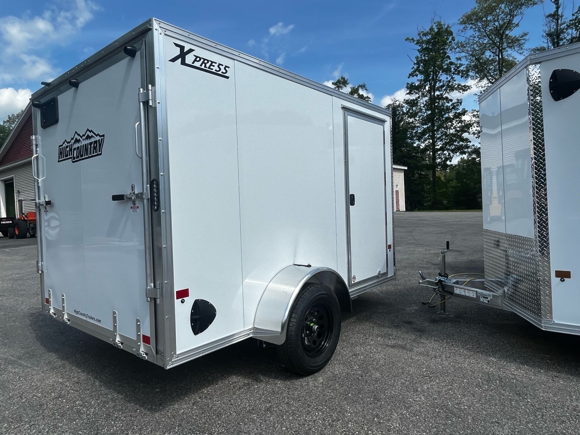 Two white trailers are parked next to each other in a parking lot.