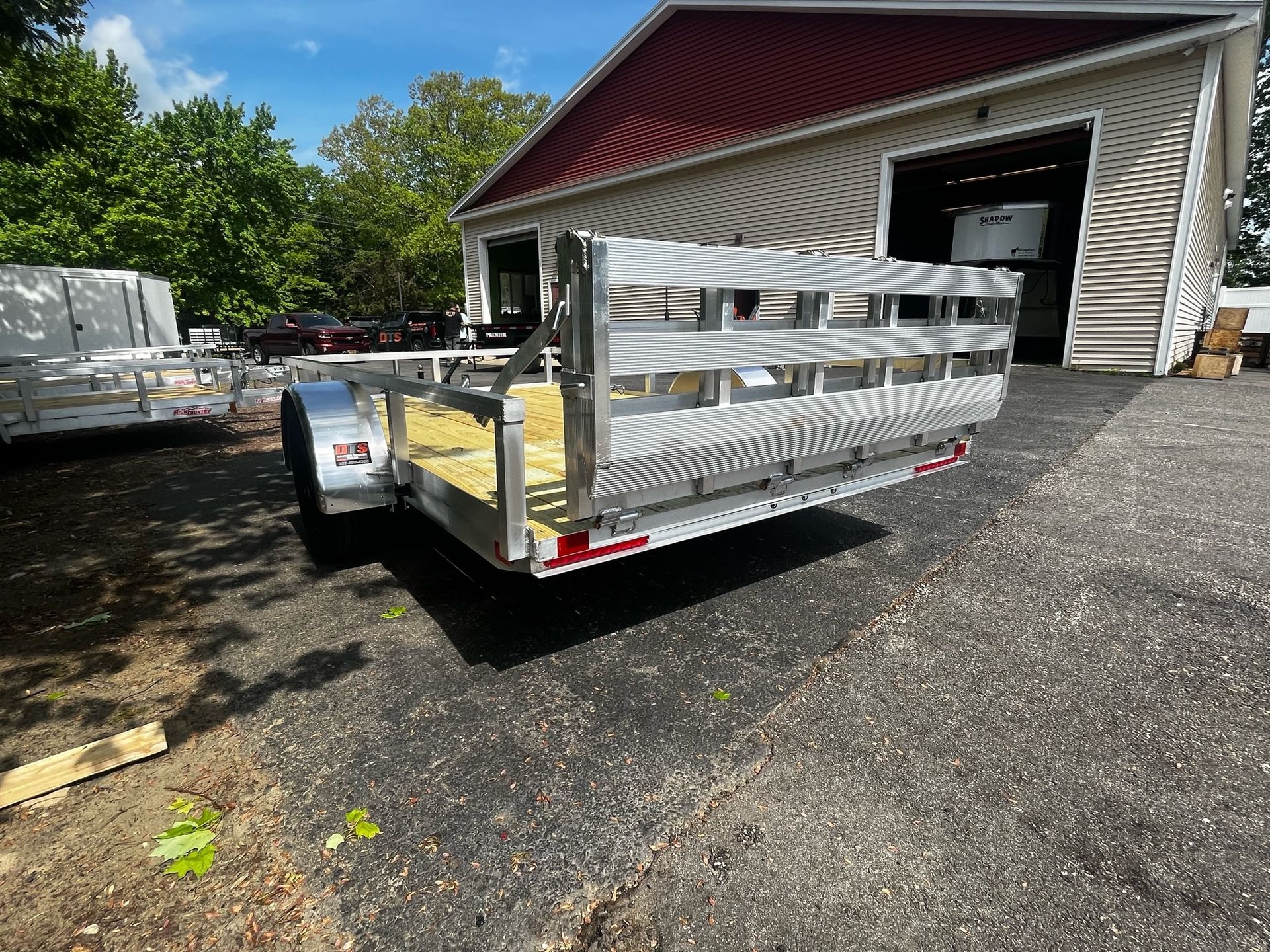 A trailer is parked in a driveway in front of a garage.