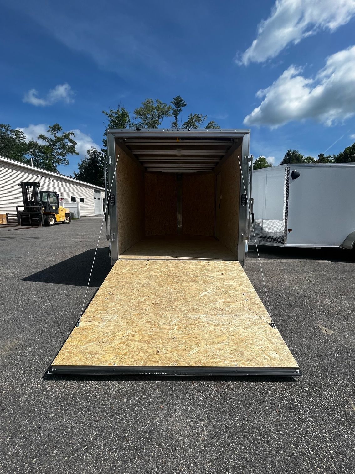 A trailer is sitting in a parking lot with the door open.